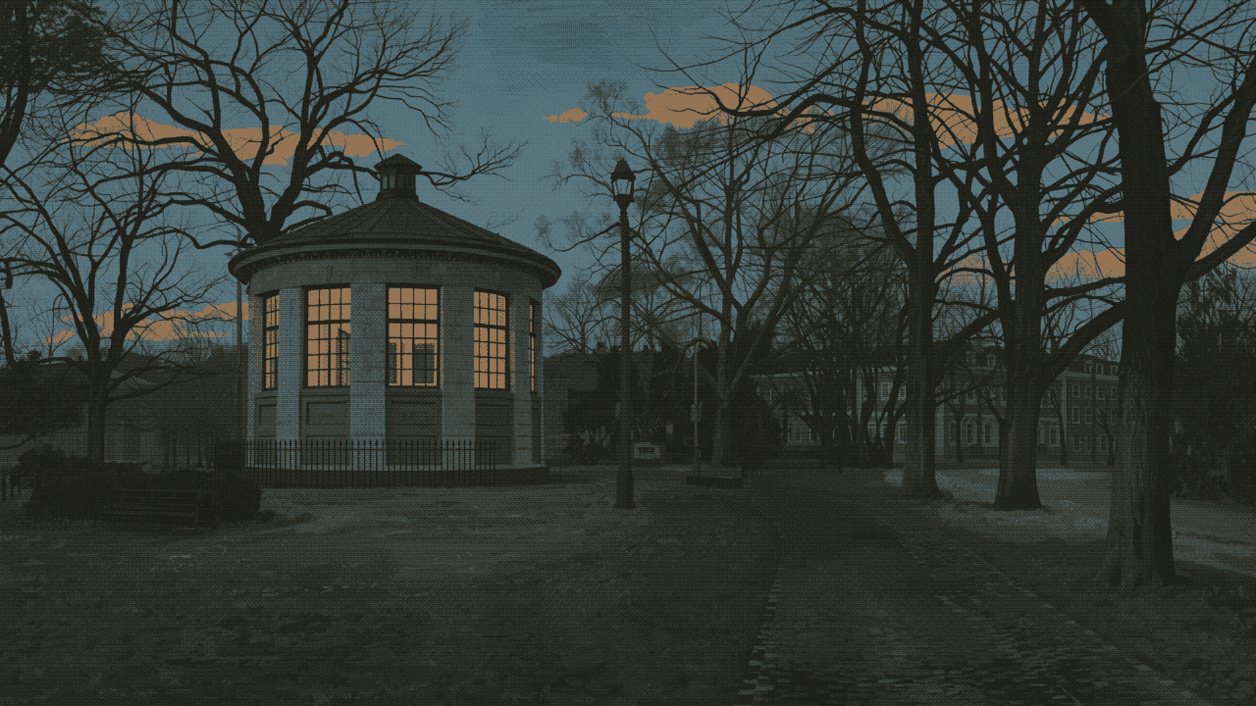 A round pavilion glowing warm in a park of bare trees at dusk